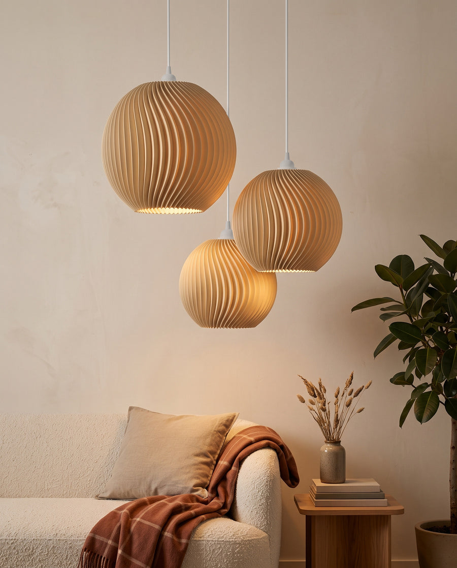 Drei Onda Lampenschirme in Beige leuchten gedimmt über dem Sofa am Abend