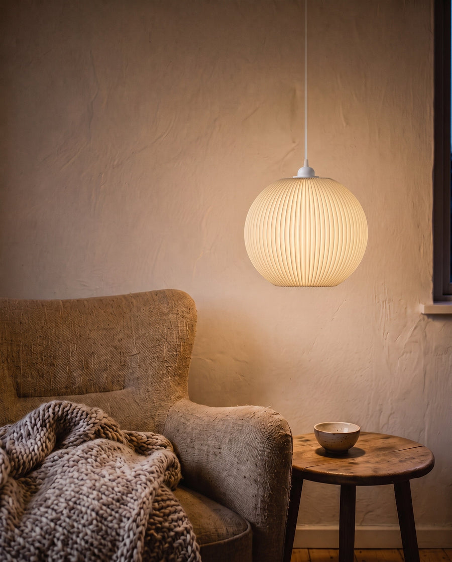 Riga Plissee-Lampenschirm Kugel in Beige, Größe XL (35 cm), leuchtet warm über der Leseecke mit Sessel am Abend