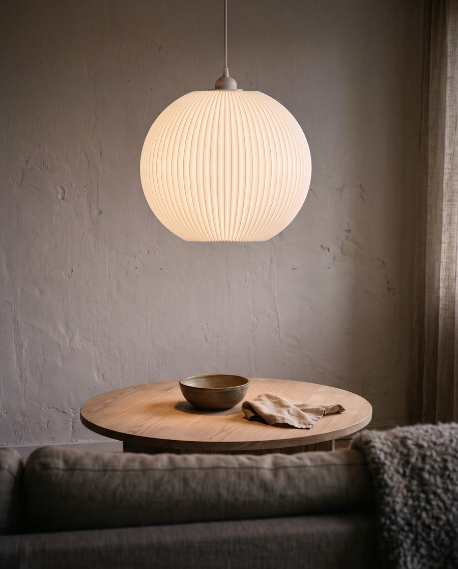 Riga Plissee-Lampenschirm Kugel in Weiß leuchtet warm über dem Couchtisch im Wohnzimmer